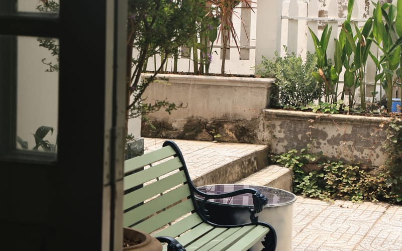 Ghế dài xanh trong vườn BRIO nhìn qua cánh cửa mở