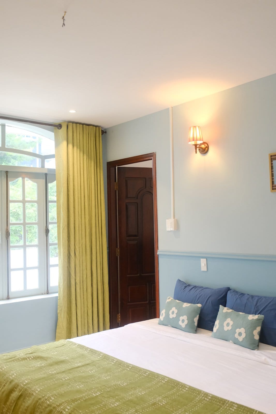 MARE bed beside the arched window and green curtain