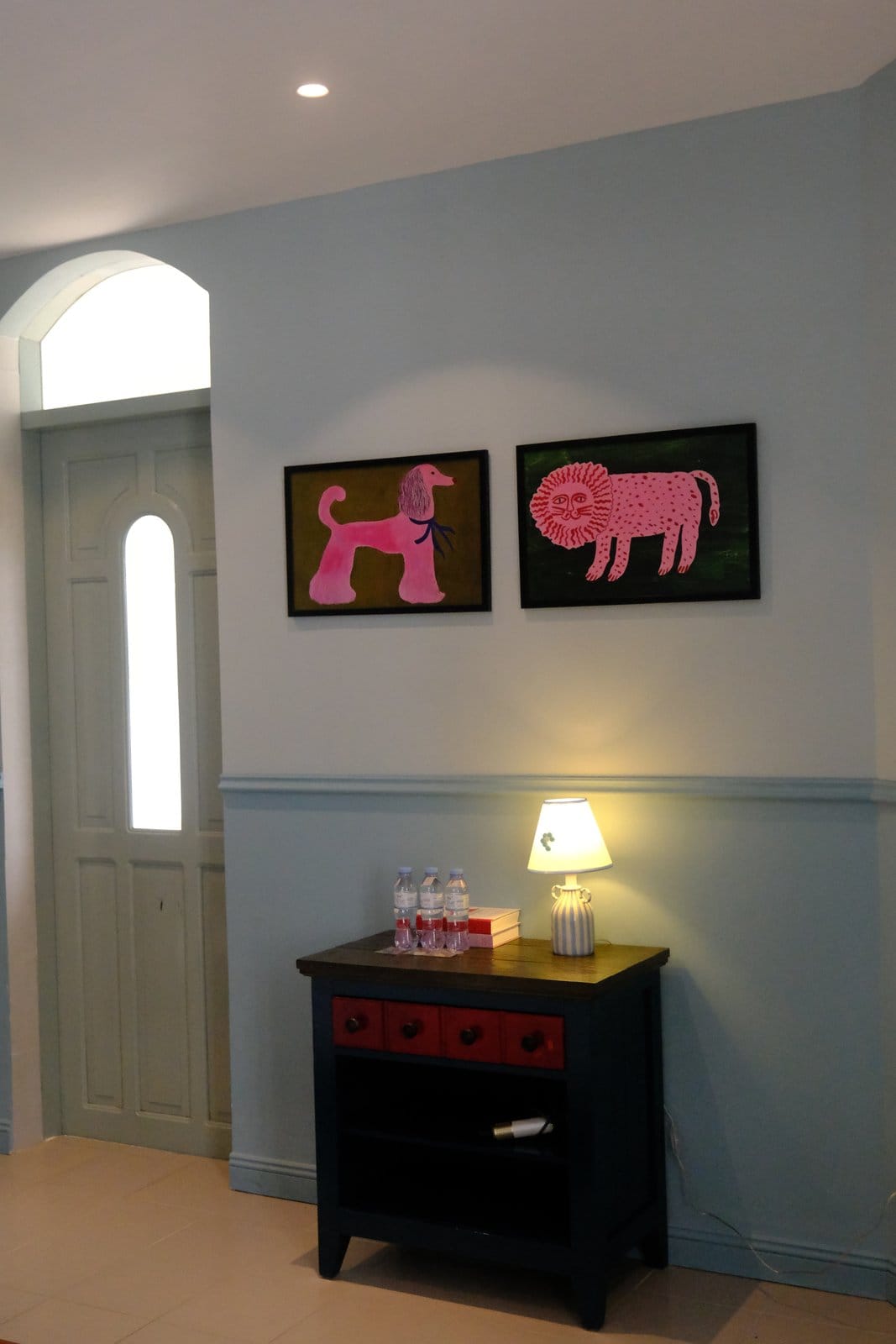 Pink dog and lion paintings above MARE's cabinet