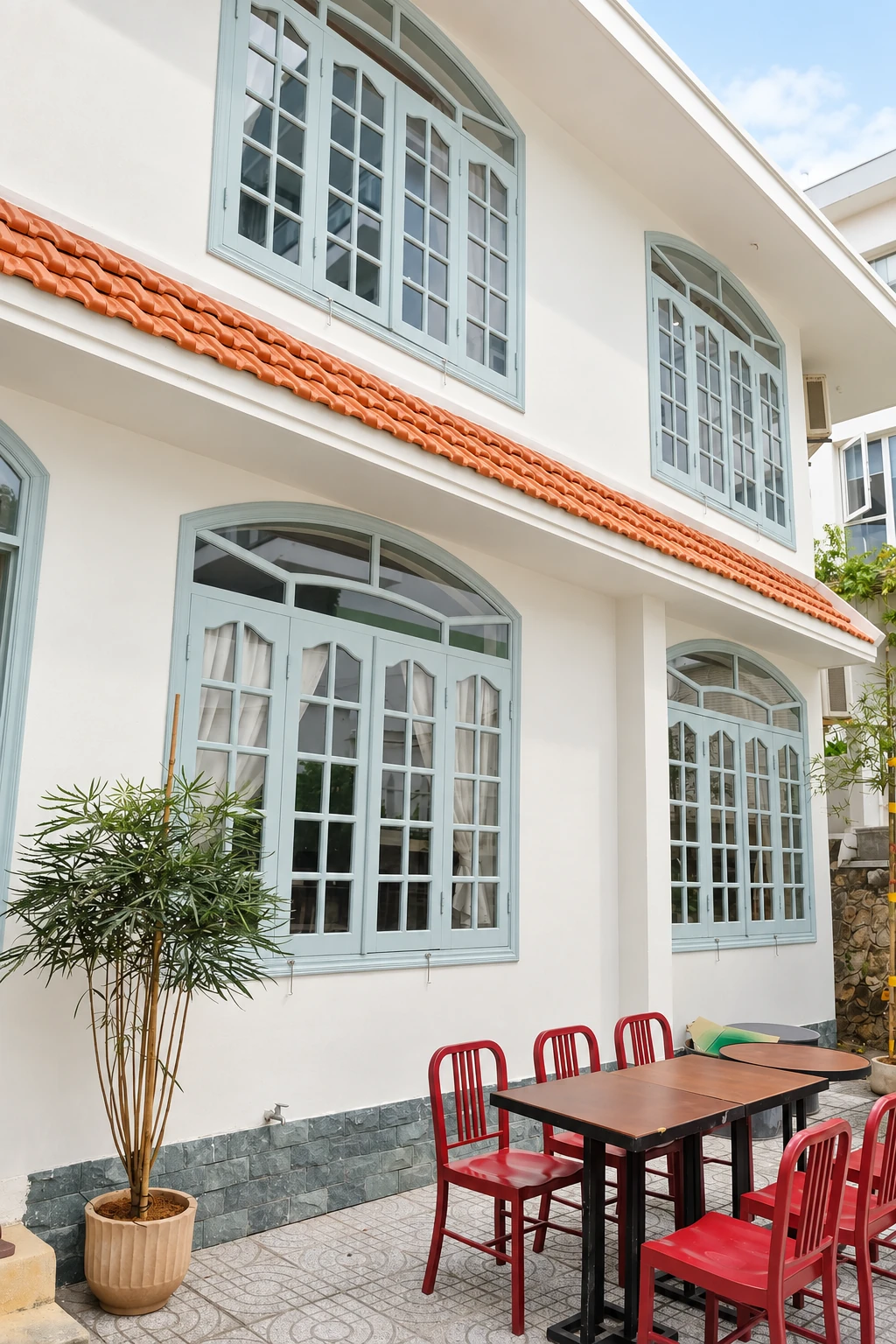 Ghế đỏ dưới những ô cửa sổ xanh nhạt ngoài sân BRIO House