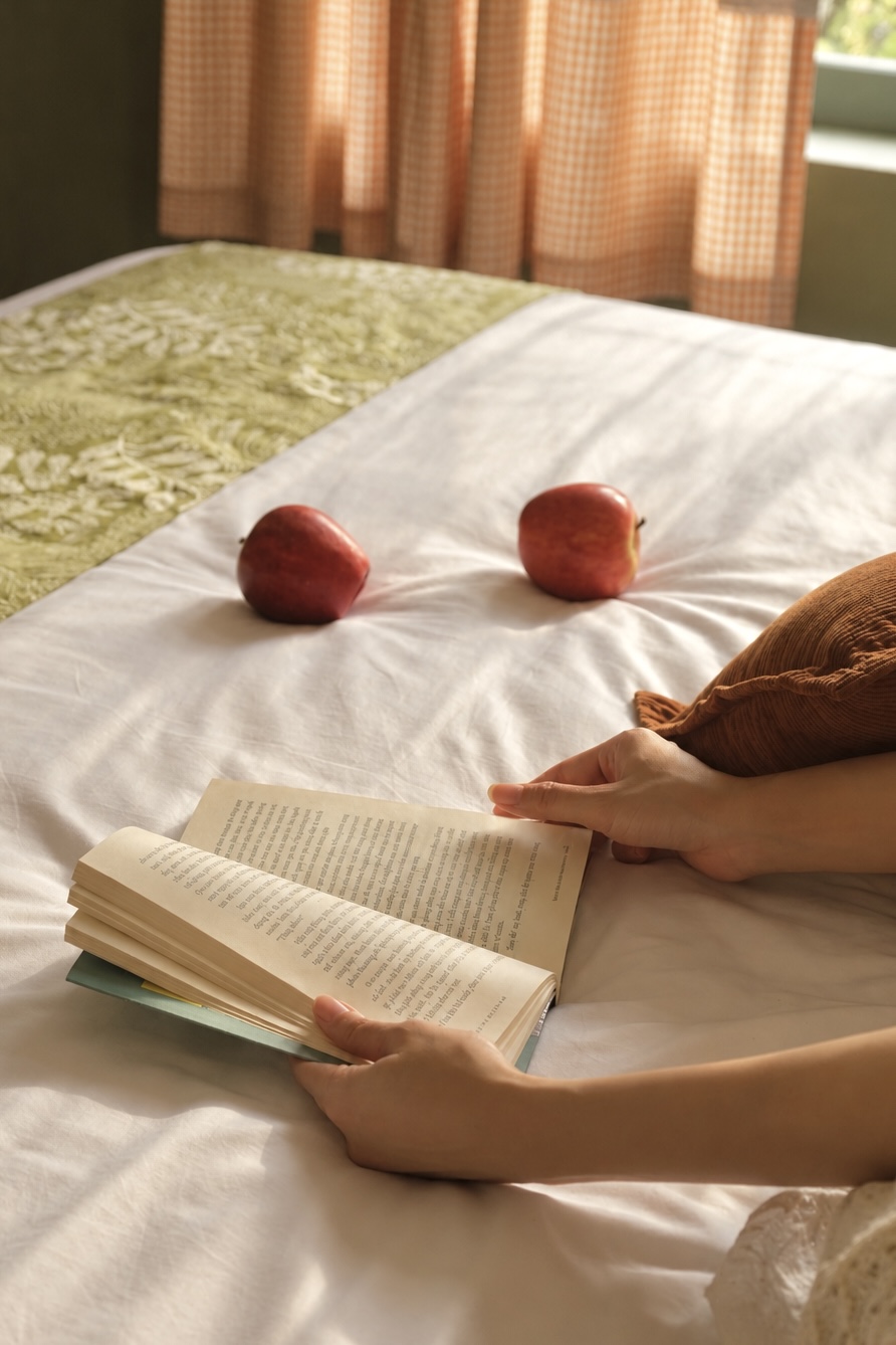 Cuốn sách mở và táo đỏ trên ga giường trắng phòng OLIVA