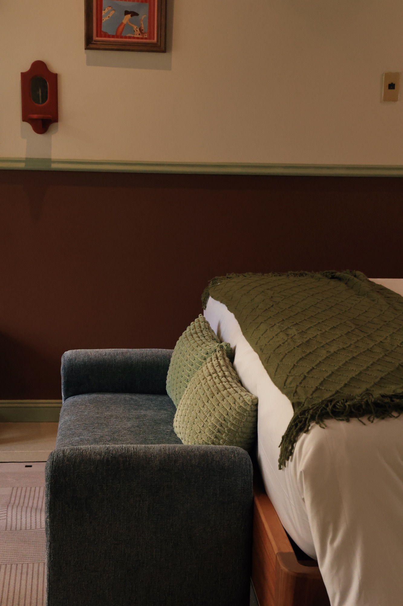 Giường, tấm phủ xanh lá và sofa nhỏ bên tường đỏ rượu phòng ROSSO