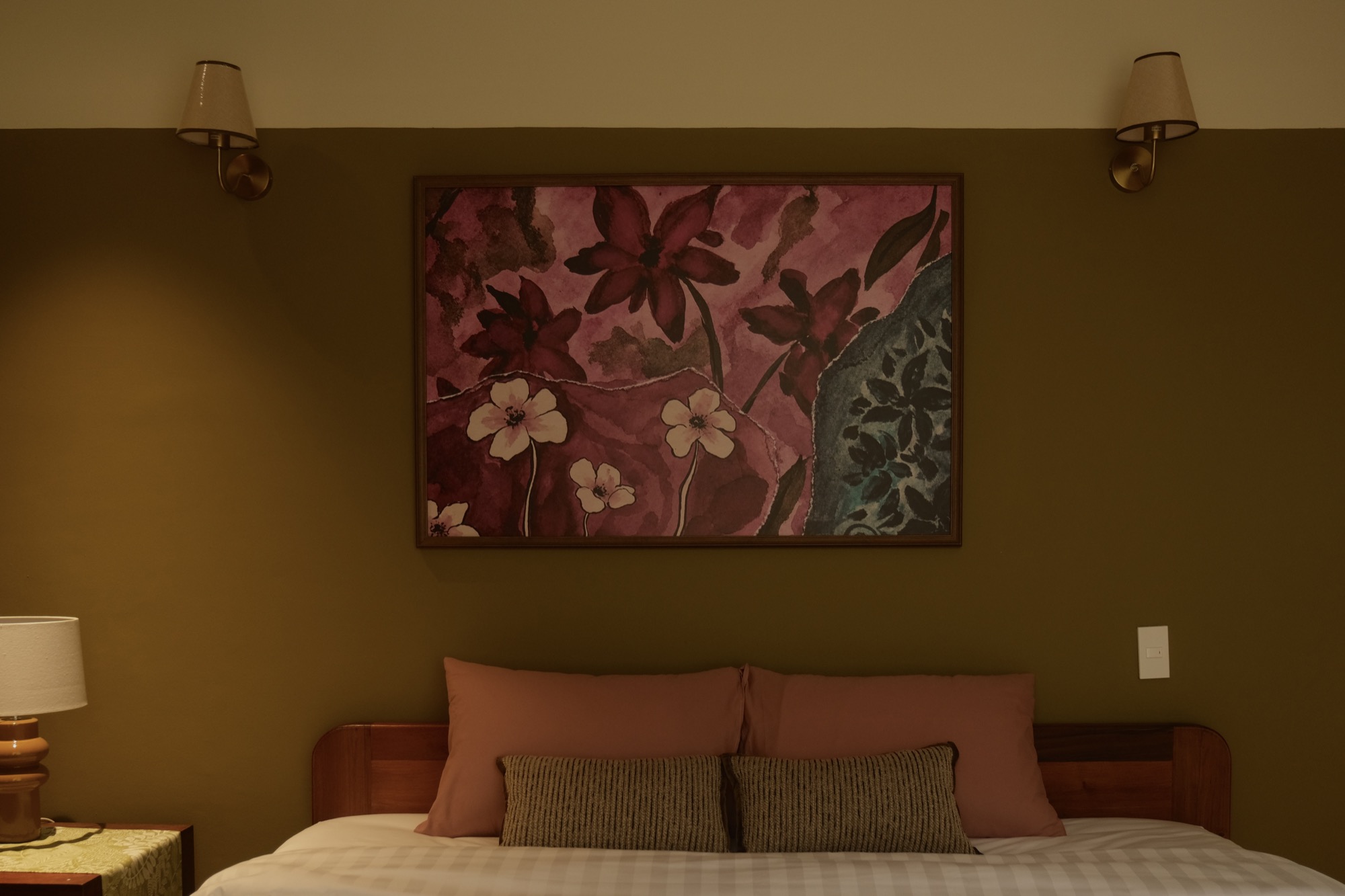 SERA's pillows and large floral artwork between two wall lights