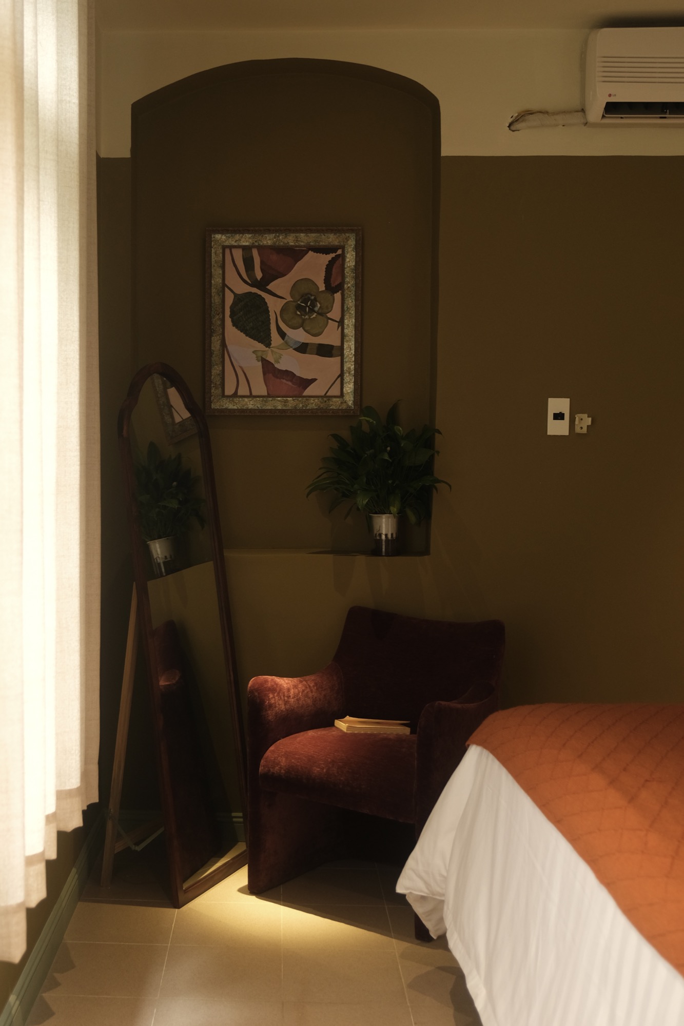 SERA's plum chair and tall mirror beside the softly lit curtain